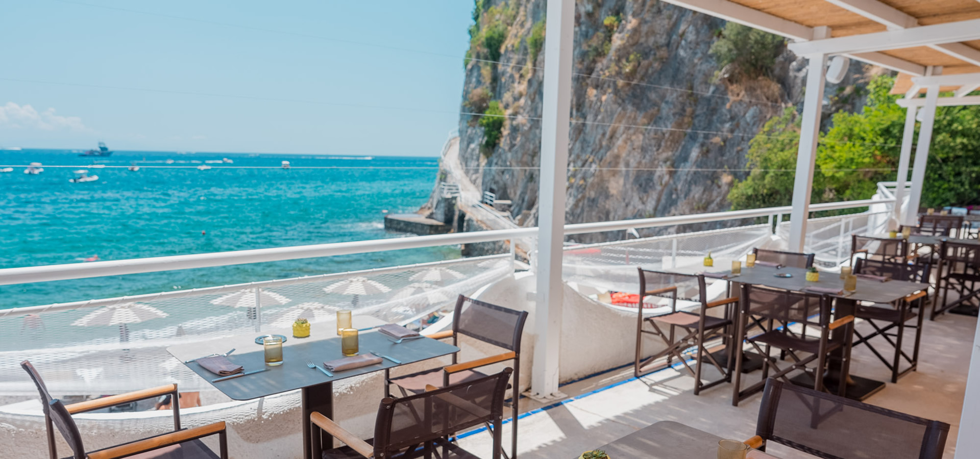 Terrazza sul mare con tavoli, sedie e vista panoramica.