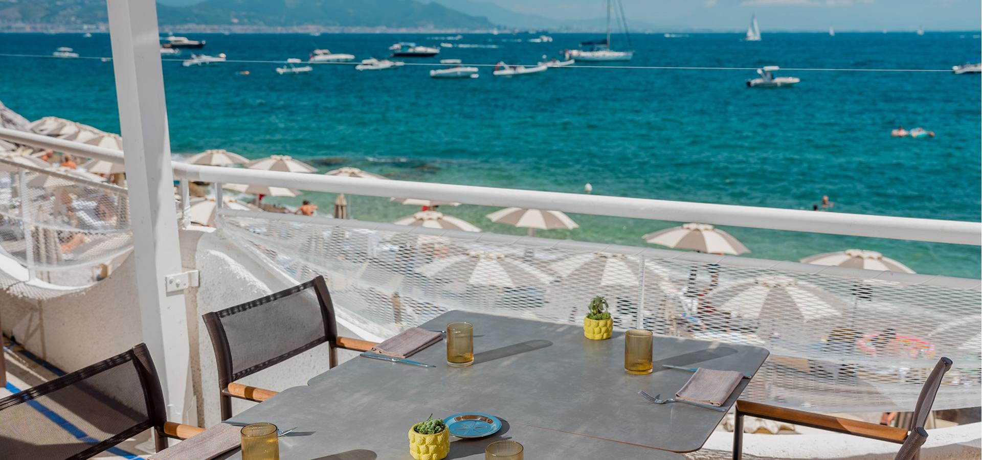 Tavolo vista mare con ombrelloni e barche in lontananza.